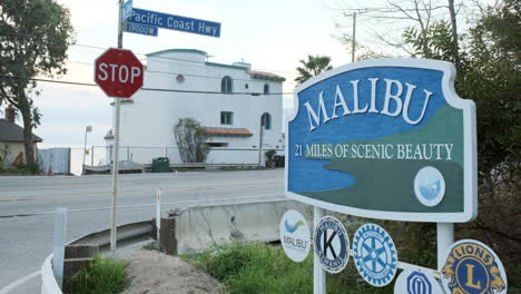 Welcome-board-of-the-scenic-city-of-Malibu-in-California-state,-with-moving-traffic-in-the-background