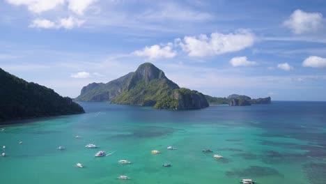 Aerial-view-pedestal-up-of-famous-huge-limestone-cliff-in-Bacuit-Archipelago-close-to-El-Nido-town,-Palawan,-the-Philippines-on-sunny-day