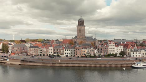 Aerial-drone-shot-backing-up-from-the-Dutch-medieval-city-of-Deventer-revealing-the-river-IJssel-that-passes-by-on-a-cloudy-day