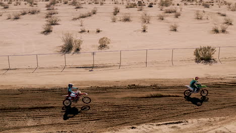 Flying-over-motocross-dirt-bikes-racing-in-slow-motion-in-Mojave-Desert,-Aerial
