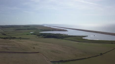 High-up-aerial-tracking-downwards-facing-towards-west-side-of-the-the-fleet-lagoon,-Portland-and-Weymouth-in-the-distance