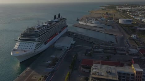 Vista-Aérea-Del-Gran-Crucero-En-El-Muelle-Junto-A-Un-Barco-Más-Pequeño-Con-Cielos-Azules