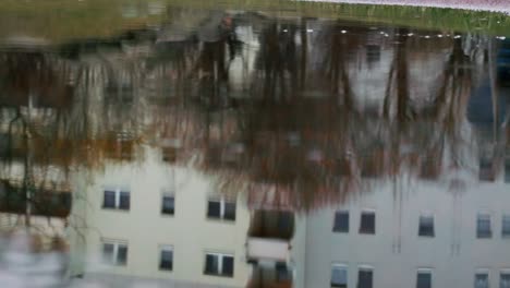 Autumn-puddle-reflection-of-grey-suburb-building-in-Berlin,-Germany