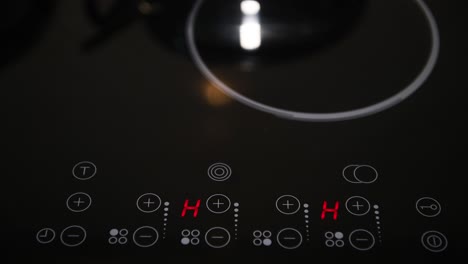 Close-up-of-electric-stove-control-panel,-red-illuminated-LED-indicators-on-shiny-black-surface,-home-appliances,-kitchen-stove