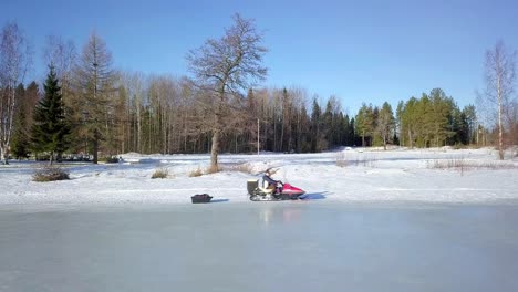 old-man-and-young-girl-on-a-snow-sled,-driving-on-frozen-ice-on-beautiful-winter-day,-downres