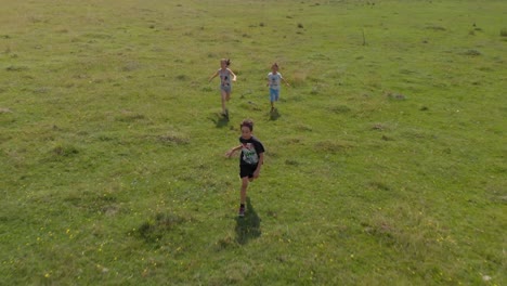Children-run-and-play-in-green-field---aerial-tracking-ahot