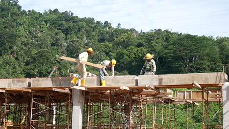 Bauarbeiter,-Die-Auf-Der-Baustelle-Holzschalungen-Und-Regenwasserrohre-Installieren