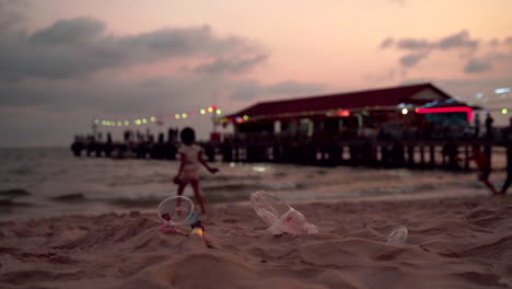 Plastic-pollution-and-a-kids-playing-on-the-background-on-a-beach-in-Sihanoukville,-Cambodia