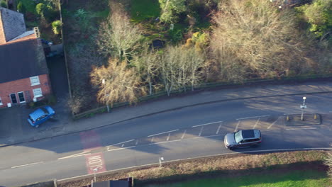 Aerial-view-tracking-a-luxury-4X4-through-a-small-village-in-the-Kent-Countryside,-UK