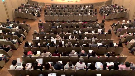 Japanese-spectators-sitting-at-a-concert-hall-with-a-program-in-their-hands