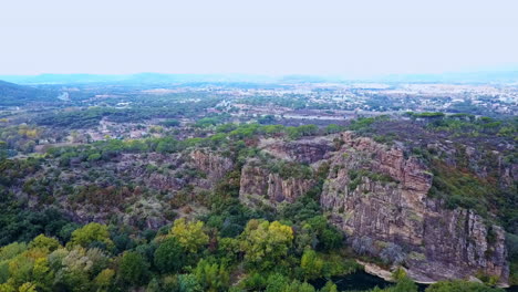 Aerial-shot-pan-right-canyon-valley-below-and-small-town-in-horizon,-South-France