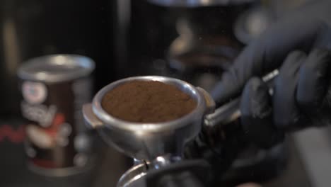 Barista-taps-ground-coffee-to-level-it-slow-motion-shallow-depth-of-field-frappe