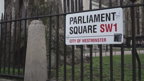 People-walking-past-Parliament-Square-street-sign-near-Westminster-Abbey-in-London