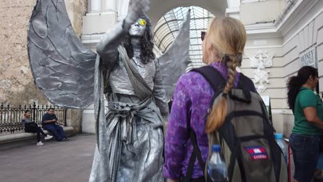 A-mime-statue-talking-in-motion-with-a-woman-giving-him-money
