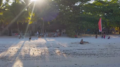 Panning-shot-of-Anda-beach,-where-tourists-are-enjoying-the-white-sand-and-a-cold-beverage-while-relaxing-in-Bohol,-Philippines