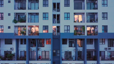 Aerial-Shot-tracking-up-High-Rise-building-showing-people-in-apartments-and-on-balconies