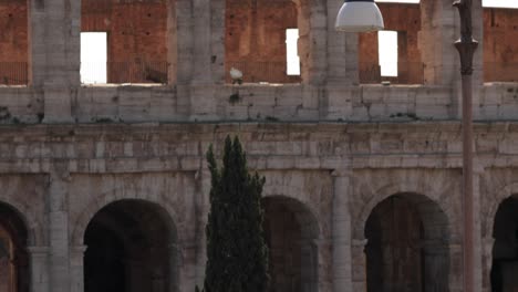 Camera-tilt-on-a-close-up-shot-of-the-the-world’s-famous-monument,-the-Colosseum-revealing-crowded-street-full-of-tourists