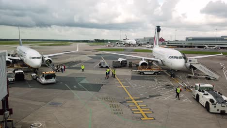 Service-personnel-on-runway-at-Manchester-airport-in-hi-vis-jackets,-preparing-a-domestic-aircraft-for-take-off,-Manchester,-UK