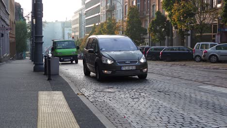 Cars-driving-on-a-street-of-Poznan,-Poland,-nobody-seems-around-buildings,-concept-design-of-city-life