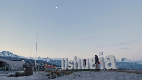 Low-Angle-Weitwinkel-Tourist,-Der-Fotos-Auf-Dem-Ushuaia-Schild-Und-Der-Mondsichel-Am-Himmel-Macht