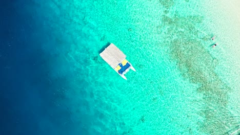 Bahamas,-Turistas-Nadando-Sobre-El-Arrecife-De-Coral,-Pequeño-Barco-Turístico-Flotando-En-El-Agua-De-Mar-Cristalina