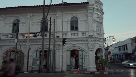 Vista-Panorámica-Del-Edificio-De-Arquitectura-Shino-portuguesa-Al-Atardecer-Con-Mucho-Tráfico-En-La-Antigua-Calle-De-La-Ciudad-De-Phuket,-Tailandia