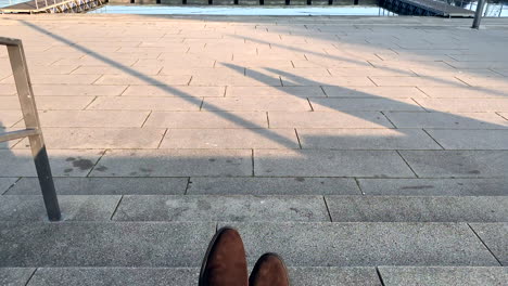 Un-Hombre-De-Negocios-Con-Zapatos-De-Cuero-Marrón-Está-Sentado-En-Las-Escaleras-Junto-Al-Lago-Después-Del-Trabajo-Al-Atardecer