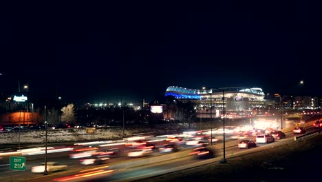 Lapso-De-Tiempo-Del-Flujo-De-Tráfico-En-La-Interestatal-Contra-Un-Fondo-Del-Estadio-De-Una-Milla-De-Alto-De-Los-Broncos-De-Denver