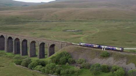 Aerial-Shot-of-a-Northern-Train-Crossing-Ribblehead-Viaduct-in-the-Yorkshire-Dales-from-Right-to-Left-with-a-Narrow-Crop