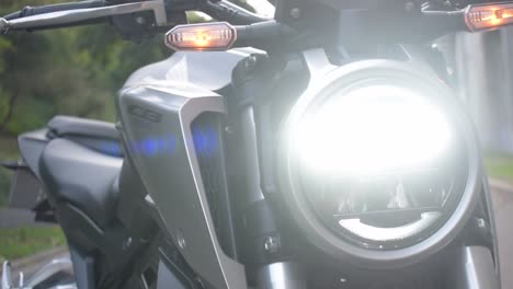 Primer-Plano-De-Las-Luces-Led-De-Una-Motocicleta-Moderna-Con-La-Puesta-De-Sol-En-El-Fondo