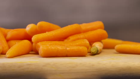 A-pile-of-fresh,-crisp,-baby-carrots-on-a-wood-cutting-board