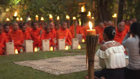 Exterior-Medium-Slow-Motion-Shot-of-Ladies-Praying-in-Front-of-Lots-of-Monks-in-Evening