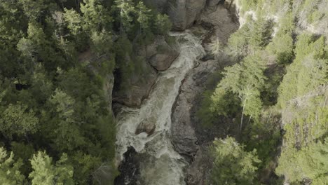 Drone-shot-flying-forwards-with-the-camera-tilted,-flying-over-rapids-in-a-canyon