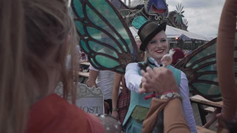 Female-entertainer-with-beautiful-plastic-insect-wings-gives-a-lollipop-to-festival-visitor