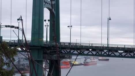 Cars-and-busses-driving-across-suspension-bridge-with-tankers-anchored-in-the-background-on-an-overcast-winter-day