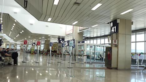 Deutlich-Wenige-Menschen-Im-Abflugbereich-Des-Internationalen-Flughafens-Von-Rio-De-Janeiro-Während-Des-Ausbruchs-Der-Covid-19-Coronavirus-Pandemie-Mit-Schildern,-Die-Die-Verhaltensregeln-Am-Gate-Darstellen