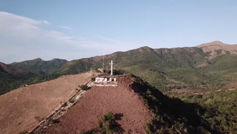 Eine-Luftaufnahme-Der-Annäherung-An-Ein-Riesiges-Kreuz-Auf-Dem-Gipfel-Des-Berges-Patyas-Mit-Blick-Auf-Die-Stadt-Coron