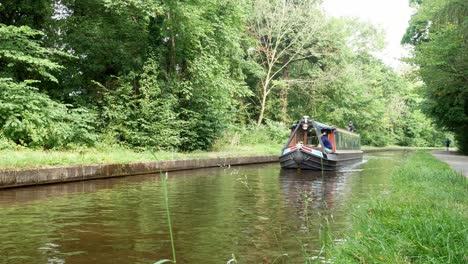 British-staycation-canal-boats-tourism-steering-through-calming-Welsh-woodland-greenery-tranquil-scene