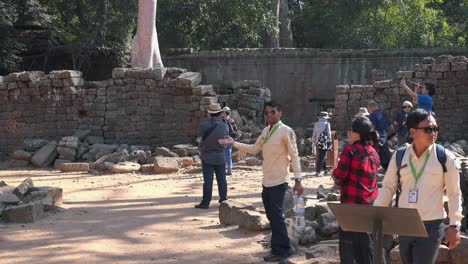 Amplia-Toma-Externa-De-Guías-Turísticos-Y-Turistas-Fuera-De-Un-Antiguo-Muro-De-Piedra-Tomando-Fotos-Cerca-De-Angkor-Wat