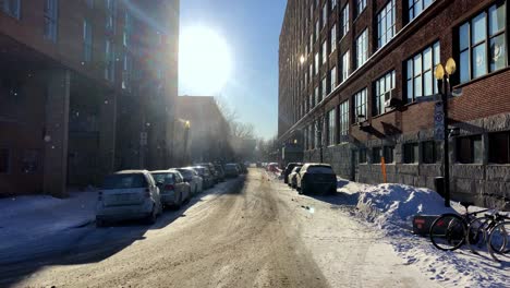 Montreal-snow-covered-street,-sun-shining-and-flurries-falling-after-winter-storm