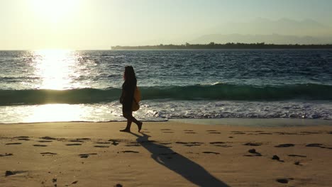 silhouette-of-the-young-woman-walking-barefoot-along-the-sandy-tropical-beach