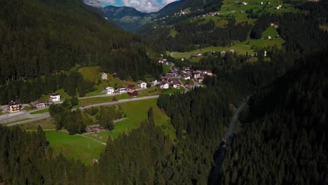 Traditional-village-town-at-Dolomite-mountains-in-northern-Italy-on-a-sunny-day,-Aerial-drone-dolly-in-reveal-shot
