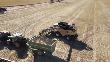 Descending-aerial-view-of-a-combine-unloading-corn-into-a-tractor-trailer