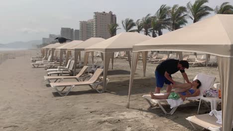 Massage-on-Beach-of-Acapulco-Mexico,-Female-Tourist-Relaxation-Under-Canopy-Sunshade,-Static-Shot