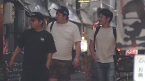 Grupo-De-Japoneses-Caminando-Por-La-Calle-Y-Mirando-Alrededor-De-Los-Restaurantes-Y-Pubs-Por-La-Noche-En-Kamata,-Ciudad-De-Oto-En-Tokio,-Japón