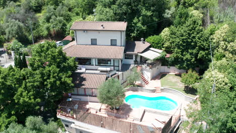 Slow-aerial-dolly-of-small-Mediterranean-villa-with-pool-surrounded-by-trees