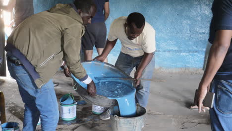 Un-Grupo-De-Voluntarios-Vierte-Pintura-De-Un-Contenedor-A-Otro