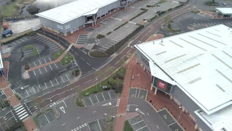 Aerial-view-above-urban-shopping-centre-empty-parking-spaces-closed-COVID-virus-town-lock-down-forward-tilt-down