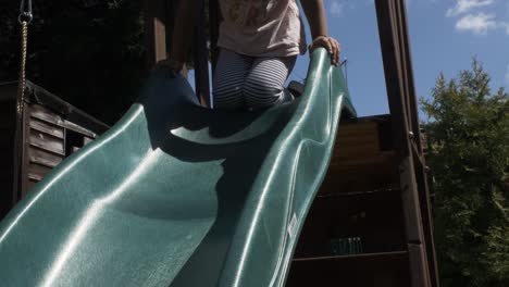 Adorable-Four-Year-Old-Girl-Climbing-Playframe-To-Use-Slide-In-Garden