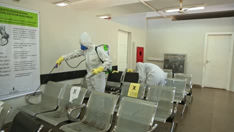 Two-soldiers-in-protective-gear-sanitize-a-hospital-chairs-after-COVID19-contamination